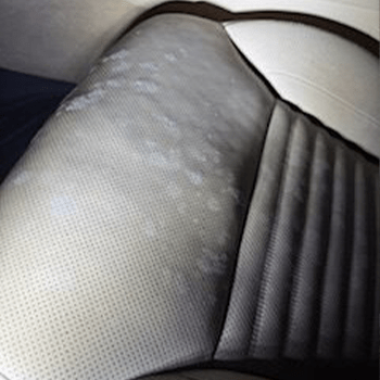 Stained leather car seat with noticeable discoloration and water spots, highlighting the need for cleaning or maintenance.
